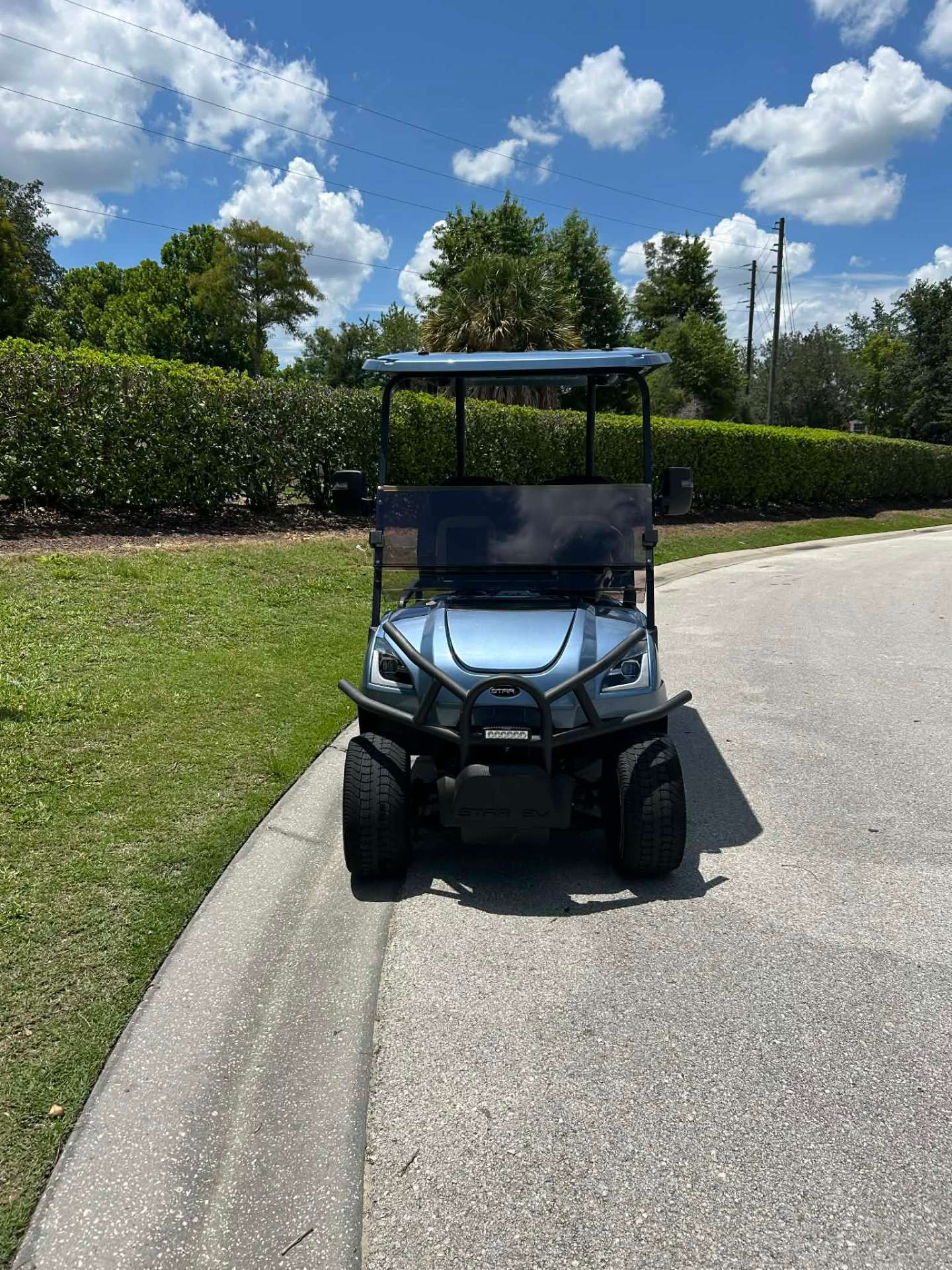 Light blue Star EV lifted golf cart on a resort walking path