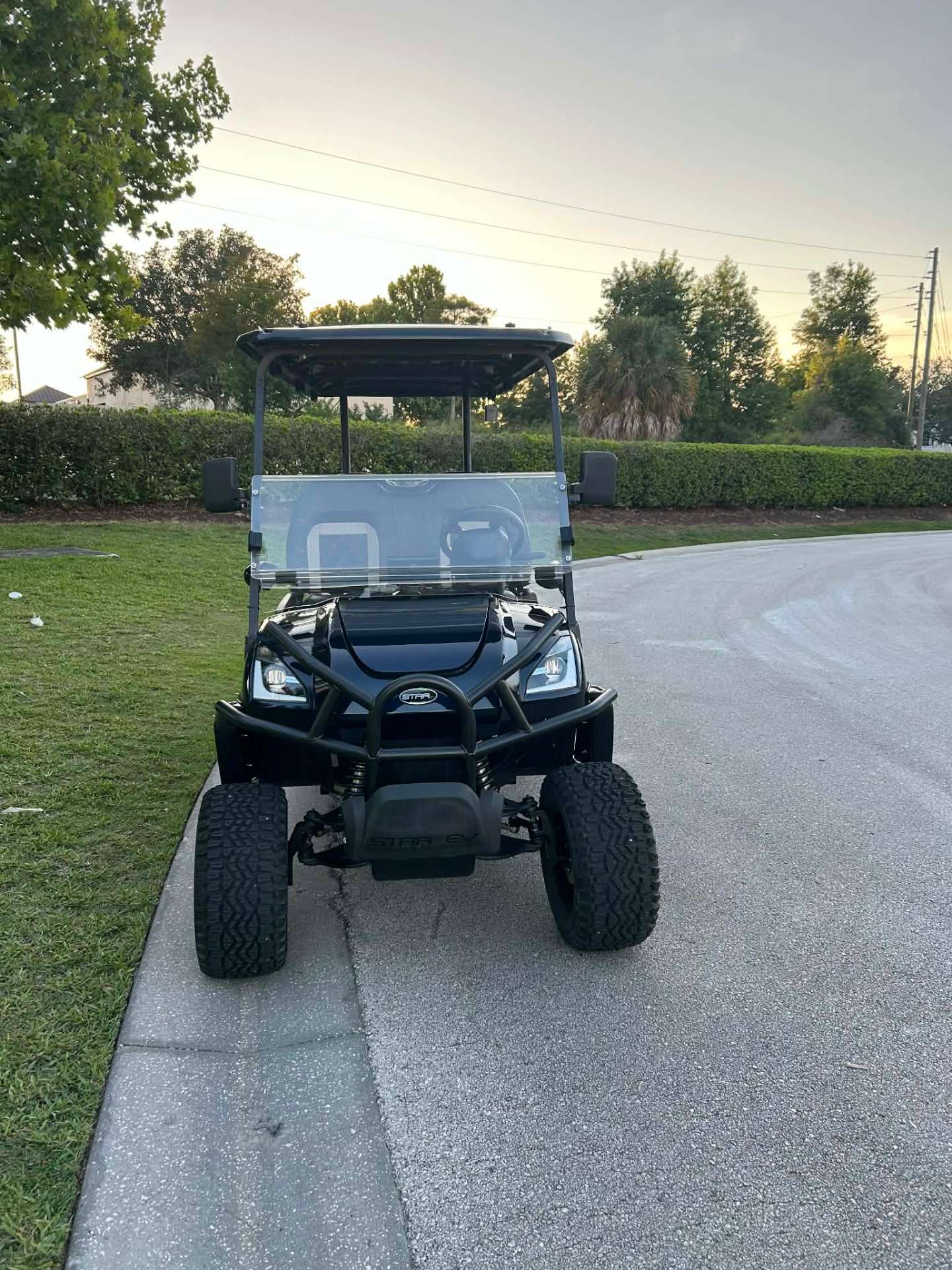 Front view of black Star EV lifted golf cart at sunset on a Central Florida street
