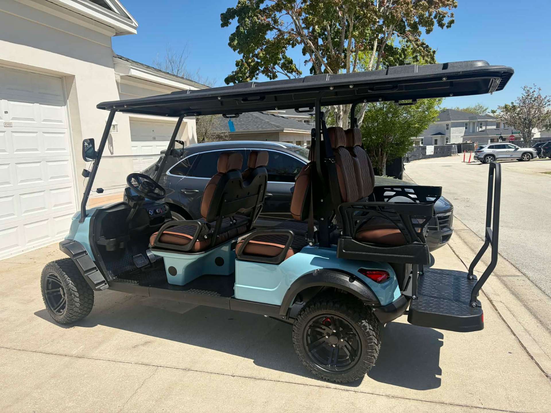 Side view of teal 6-passenger lifted golf cart in a Reunion Resort driveway