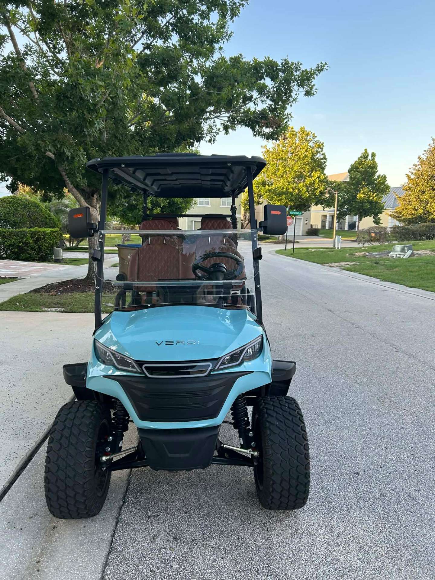 Front view of teal Verdi lifted golf cart on a Central Florida resort street