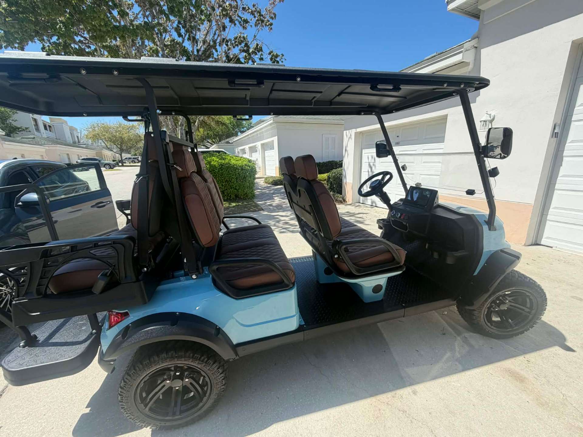 Side profile of teal 6-passenger lifted golf cart in a Central Florida driveway