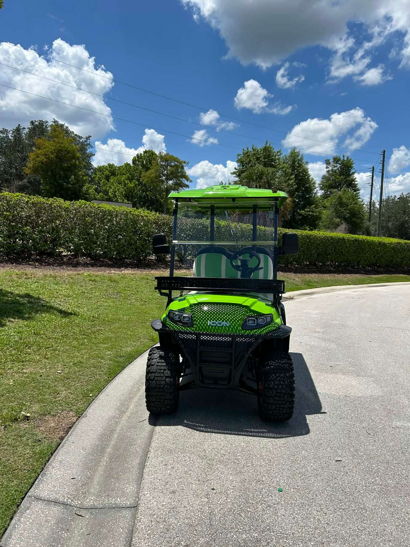 Front view of bright green ICON lifted golf cart on a Reunion Resort walking path